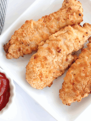 Golden crispy homemade chicken tenders served with dipping sauce.