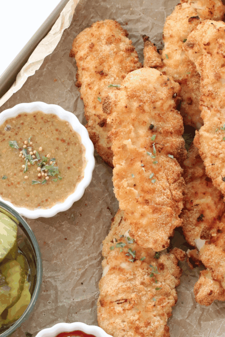 Golden crispy chicken tenders on a plate with dipping sauce