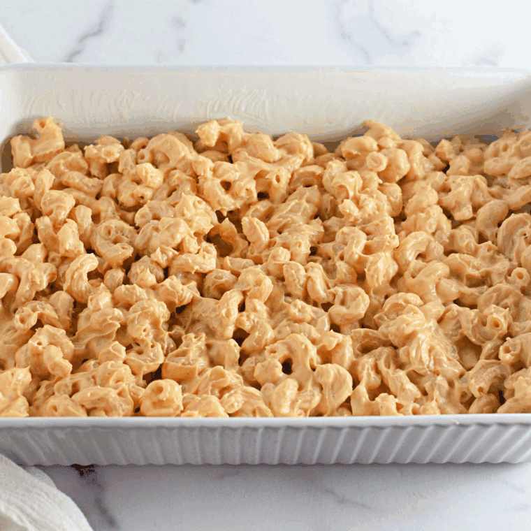 Stirring cooked macaroni into creamy cheese sauce in saucepan.