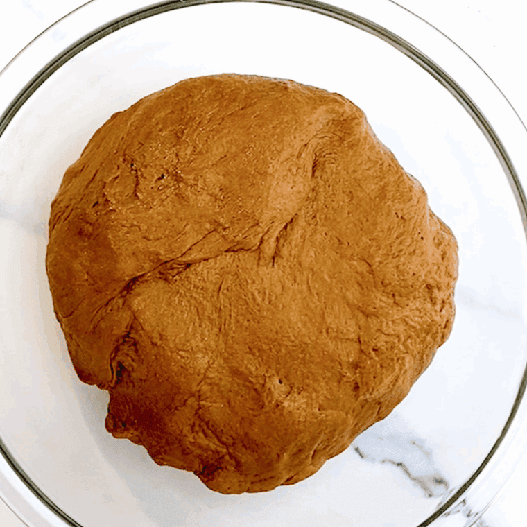 Kneading brown bread dough until smooth, then placing it in a greased bowl to rise.