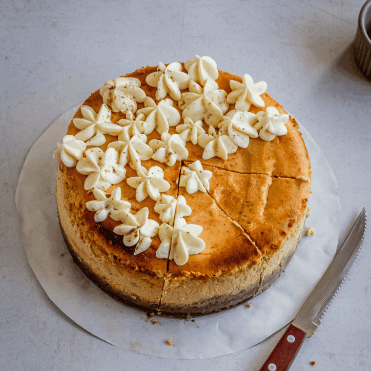 Slice of creamy pumpkin cheesecake on a graham cracker crust, topped with whipped cream like Cheesecake Factory's holiday favorite.
