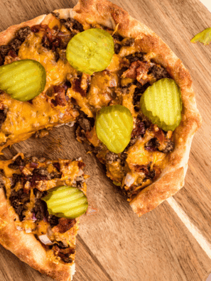 Homemade cheeseburger pizza topped with ground beef, cheddar, onions, pickles, and sauce on a golden crust.