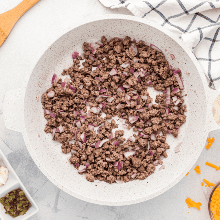 Cooking the ground beef in a skillet.