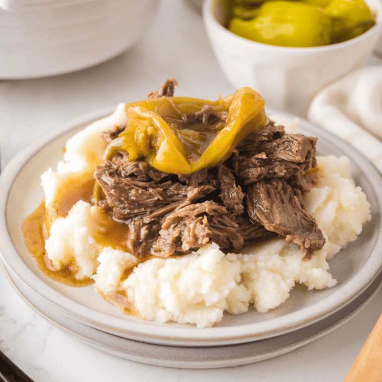 Copycat Golden Corral pot roast served over creamy mashed potatoes with brown gravy and carrots