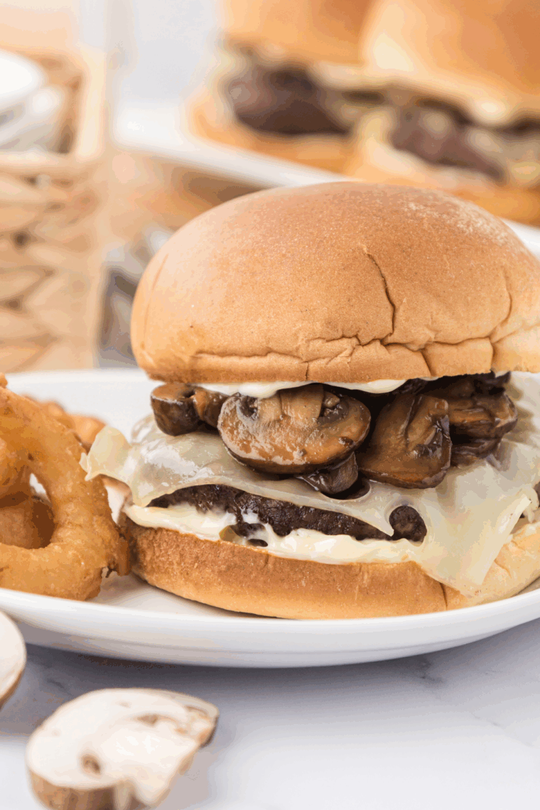 Finish burger on a plate with French fries and onion rings.