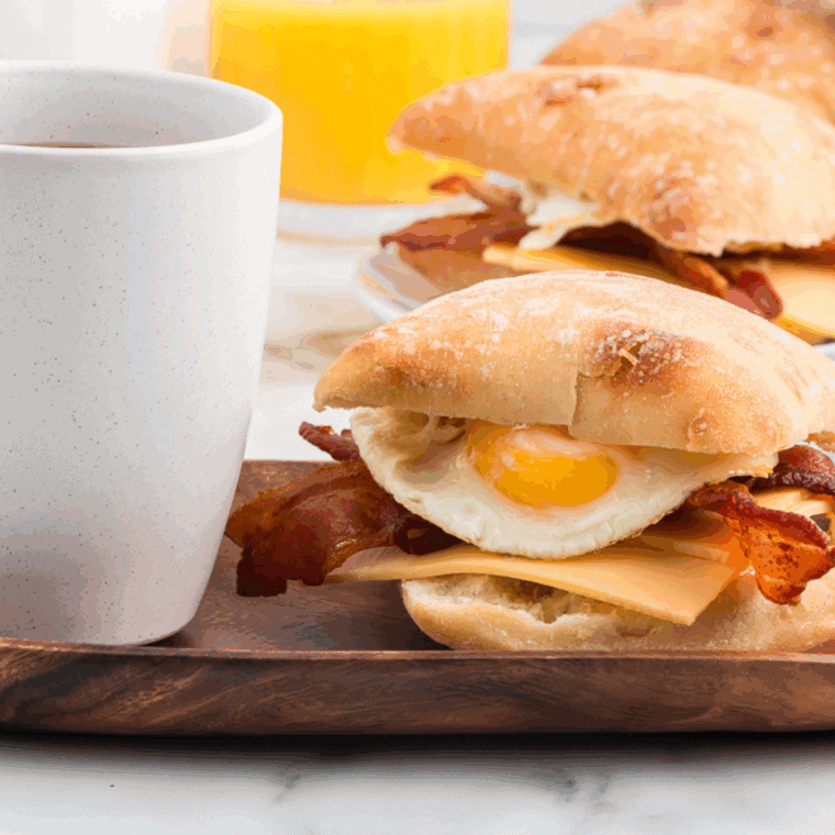  Starbucks Bacon Gouda Breakfast Sandwich on kitchen table with a cup of coffee.