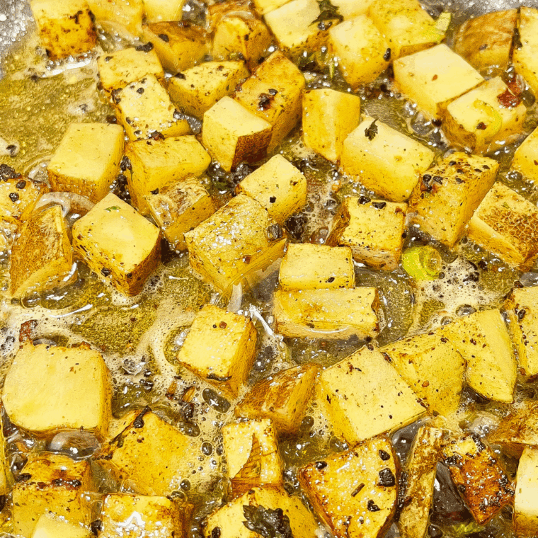 Cooking cubed potatoes in skillet with butter and pan drippings until golden and tender.