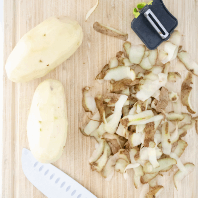 Grating peeled russet potatoes with a box grater for potato cakes.