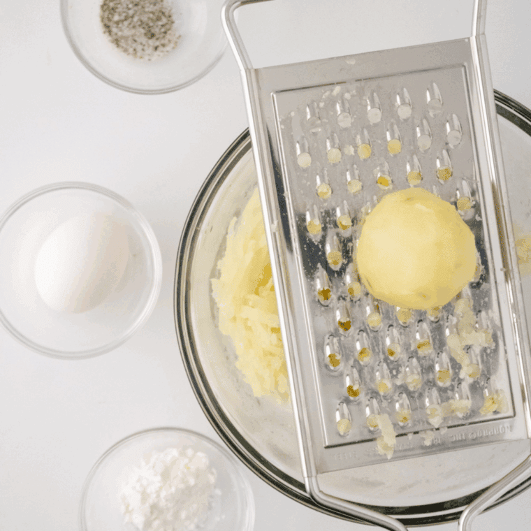Squeezing shredded potatoes in a towel to remove moisture.