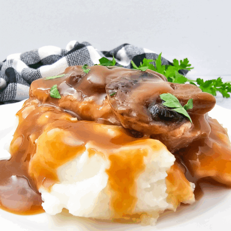 Plate of Crockpot Brown Gravy Smothered Pork Chops with mashed potatoes.