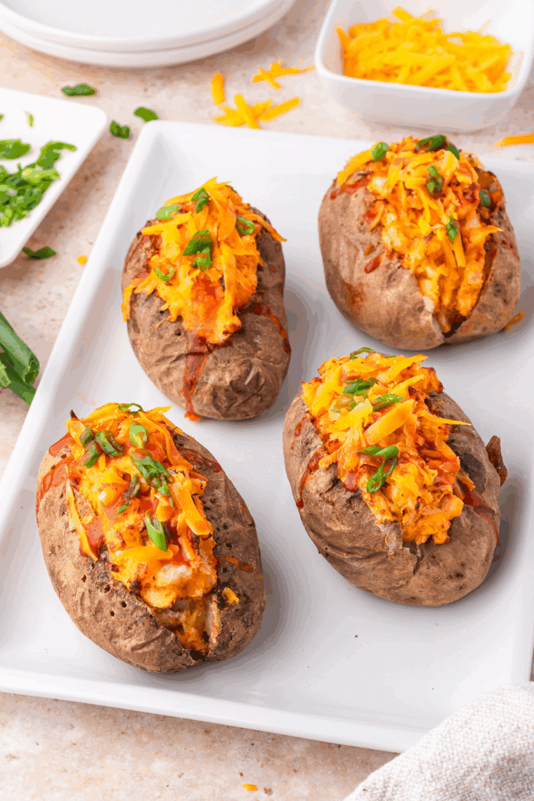 Baked potato stuffed with seasoned Mexican-style toppings including melted cheese, salsa, avocado, and green onions.