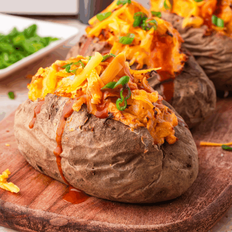 Baked potato stuffed with seasoned beans, melted cheese, salsa, and fresh cilantro on a white plate.