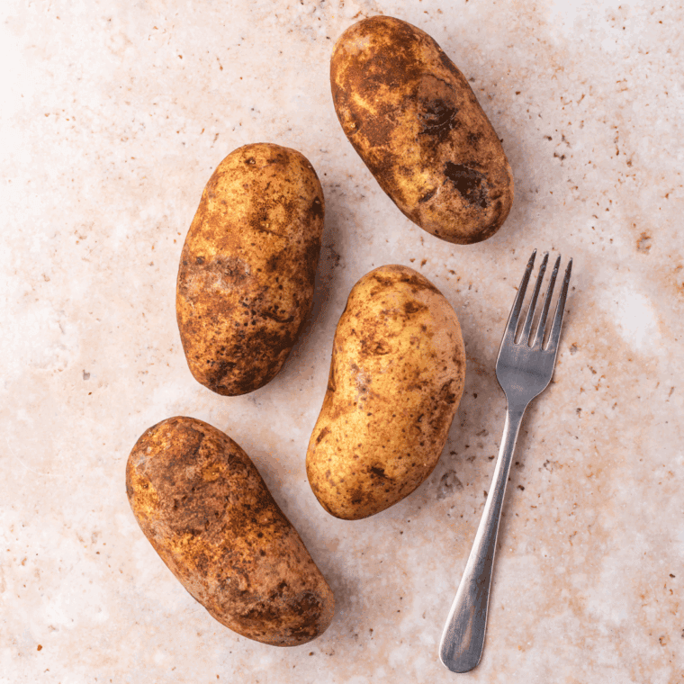Baking whole potatoes in the oven after seasoning with olive oil and salt.