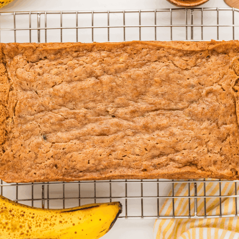 Freshly baked banana bread cooling in the pan on a wire rack.