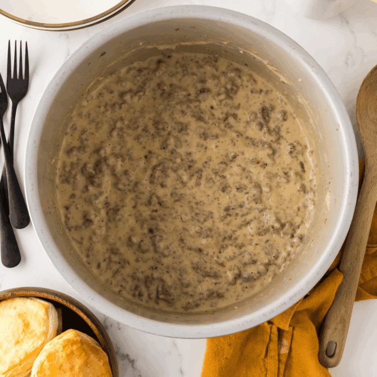 Sausage gravy with milk being stirred for thickness.