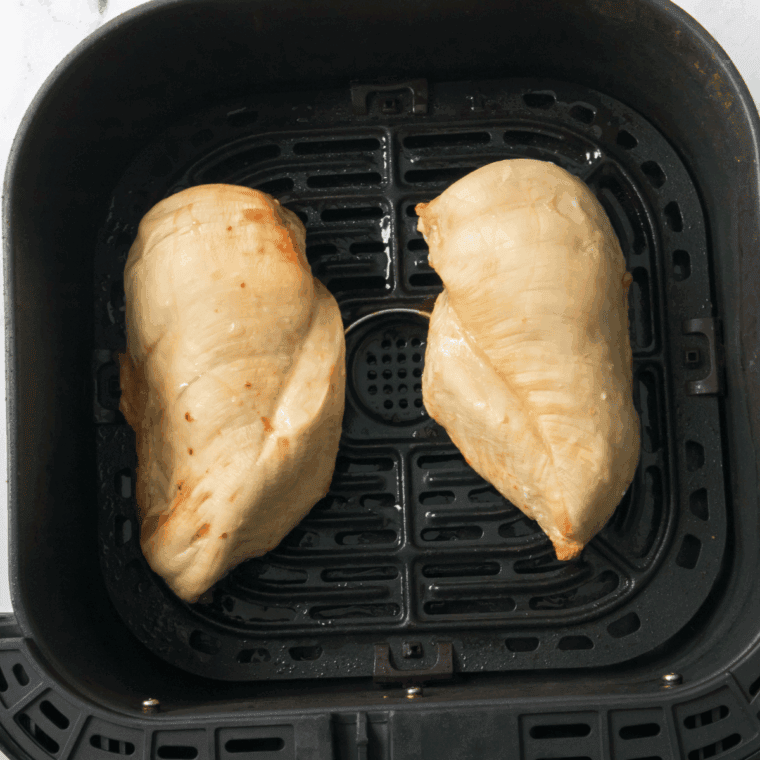 Cooked chicken breast in the air fryer basket.