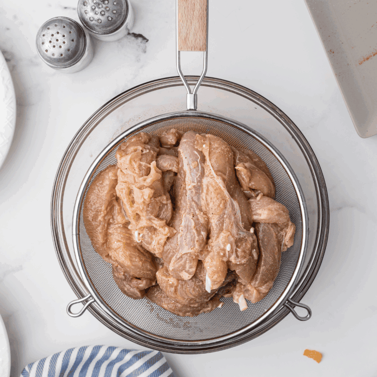 Raw chicken tenders arranged in a single layer at the bottom of a pot.