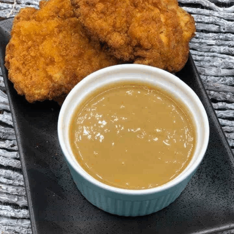 Bowl of Jack In The Box Honey Mustard Sauce with chicken tenders.