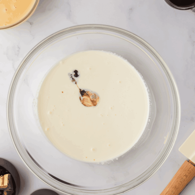 Cream cheese being whipped until smooth in a glass mixing bowl