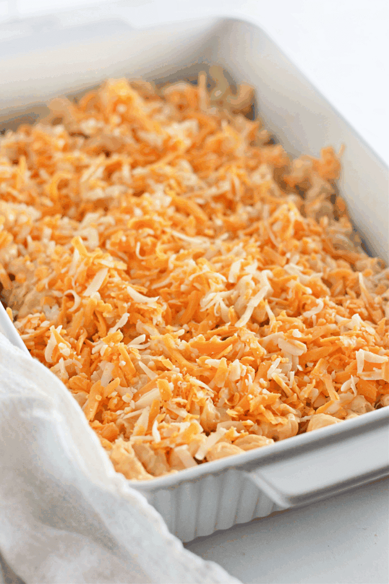 Placing the cheese on top of the Old-Fashioned Baked Macaroni and Cheese in casserole dish.