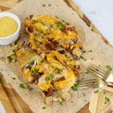 Homemade Outback Steakhouse Alice Springs Chicken topped with bacon, mushrooms, melted cheese, and honey mustard sauce on a plate.