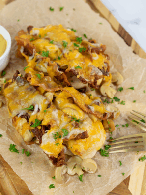 Homemade Outback Steakhouse Alice Springs Chicken topped with bacon, mushrooms, melted cheese, and honey mustard sauce on a plate.