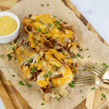 Homemade Outback Steakhouse Alice Springs Chicken topped with bacon, mushrooms, melted cheese, and honey mustard sauce on a plate.