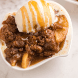 Bowl of cinnamon apple oblivion with ice cream, pecan crumble, and caramel sauce.
