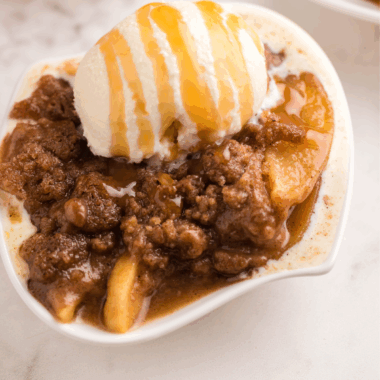 Bowl of cinnamon apple oblivion with ice cream, pecan crumble, and caramel sauce.