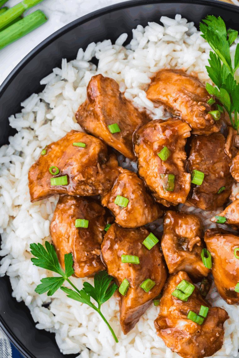 Bowl of Panda Express’s Grilled Teriyaki Chicken over rice with fresh herbs.