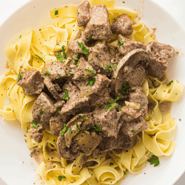 Serving creamy beef stroganoff over cooked egg noodles.