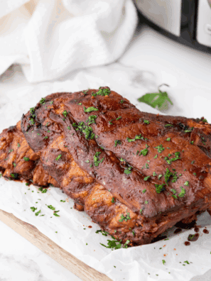 Slow Cooker Dr. Pepper ribs brushed with BBQ sauce on a baking sheet, caramelized to perfection.