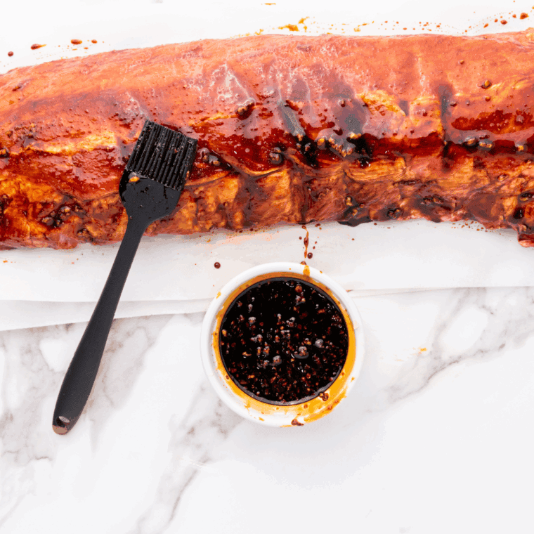 Rubbing spice blend onto raw ribs with paprika and garlic powder.