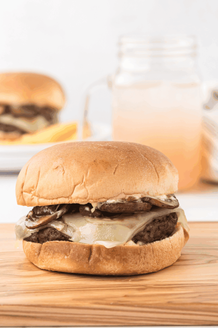 A small bowl of Smashburger Smash Sauce with a spoon, surrounded by burger ingredients on a wooden board.