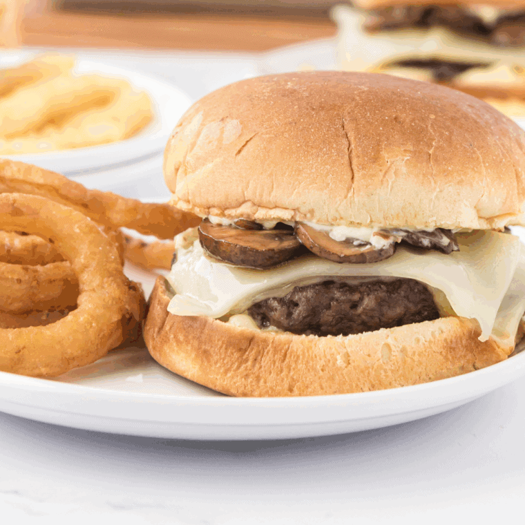 Bowl of creamy Smashburger-style sauce with a spoon, surrounded by burger fixings.