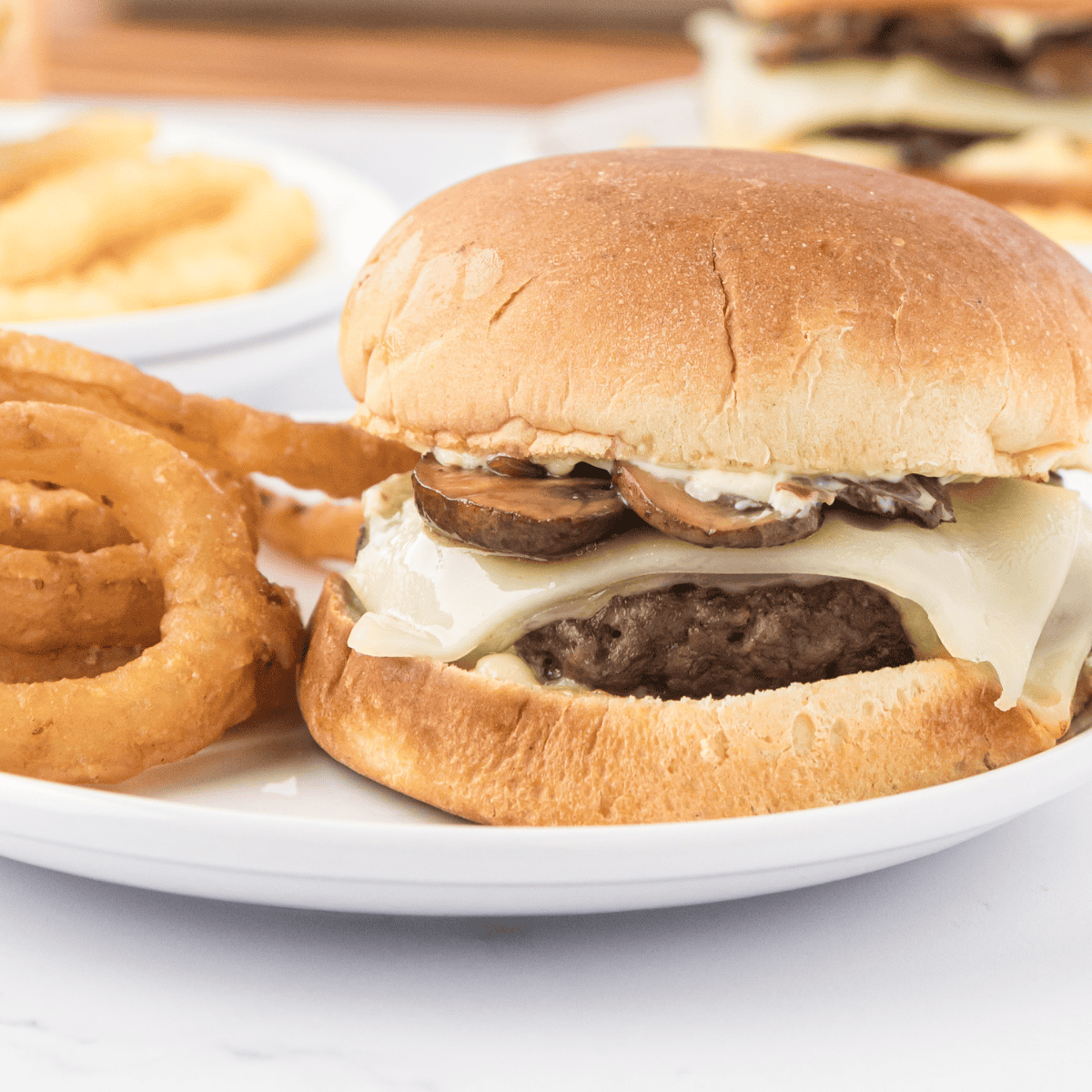 Bowl of creamy Smashburger-style sauce with a spoon, surrounded by burger fixings.