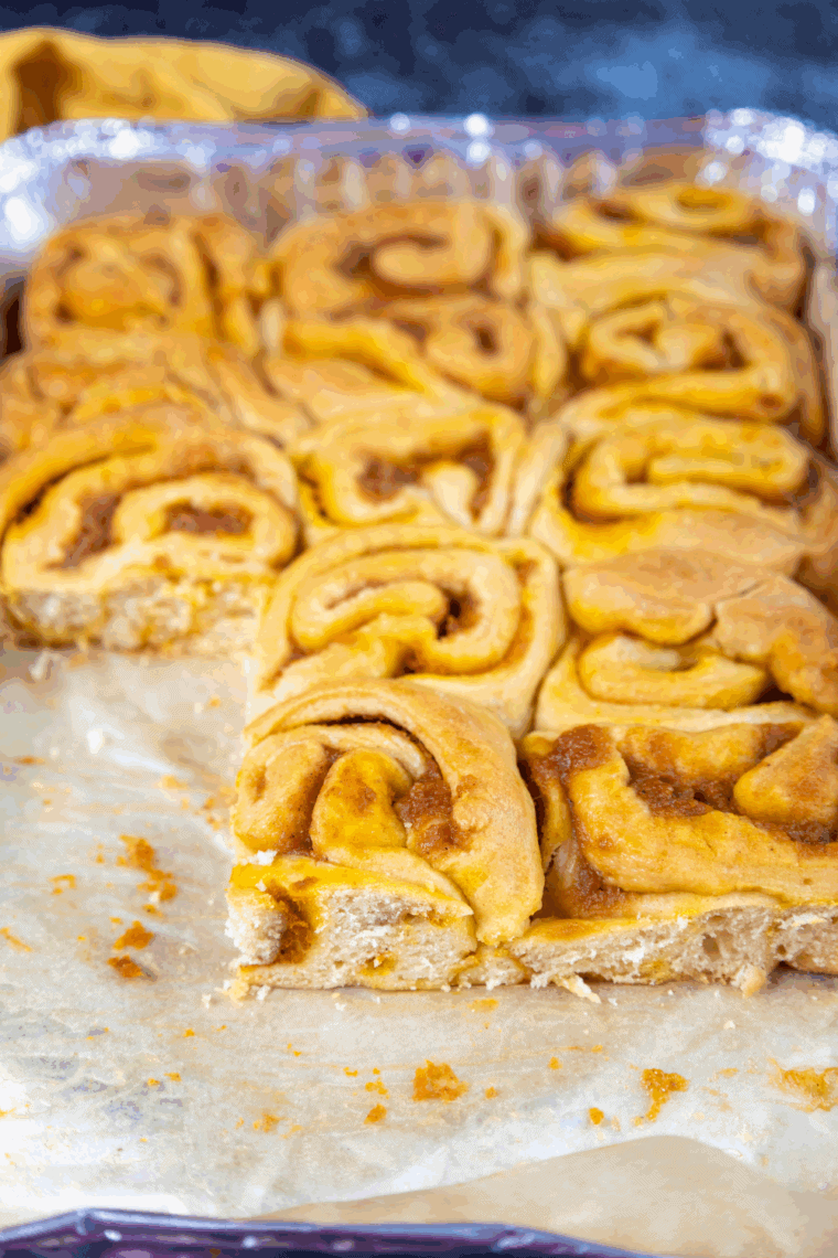 Freshly baked sourdough pumpkin cinnamon rolls drizzled with creamy glaze.