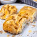 Fluffy sourdough pumpkin cinnamon rolls topped with creamy frosting.