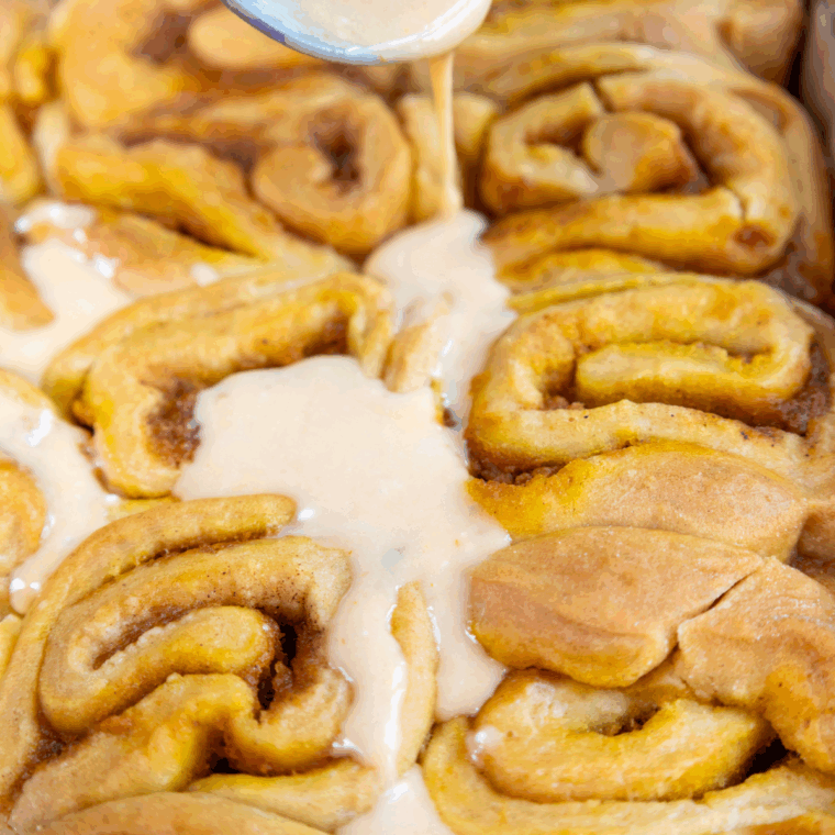 Freshly baked sourdough pumpkin cinnamon rolls drizzled with sweet glaze.