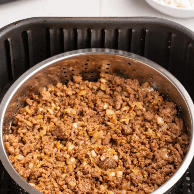 Cooked taco meat in the air fryer basket.