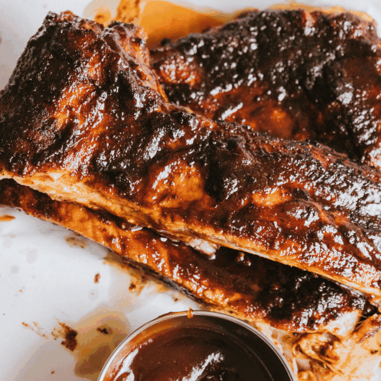 Texas Roadhouse Killer Ribs served on a plate with BBQ glaze and a side of dipping sauce.