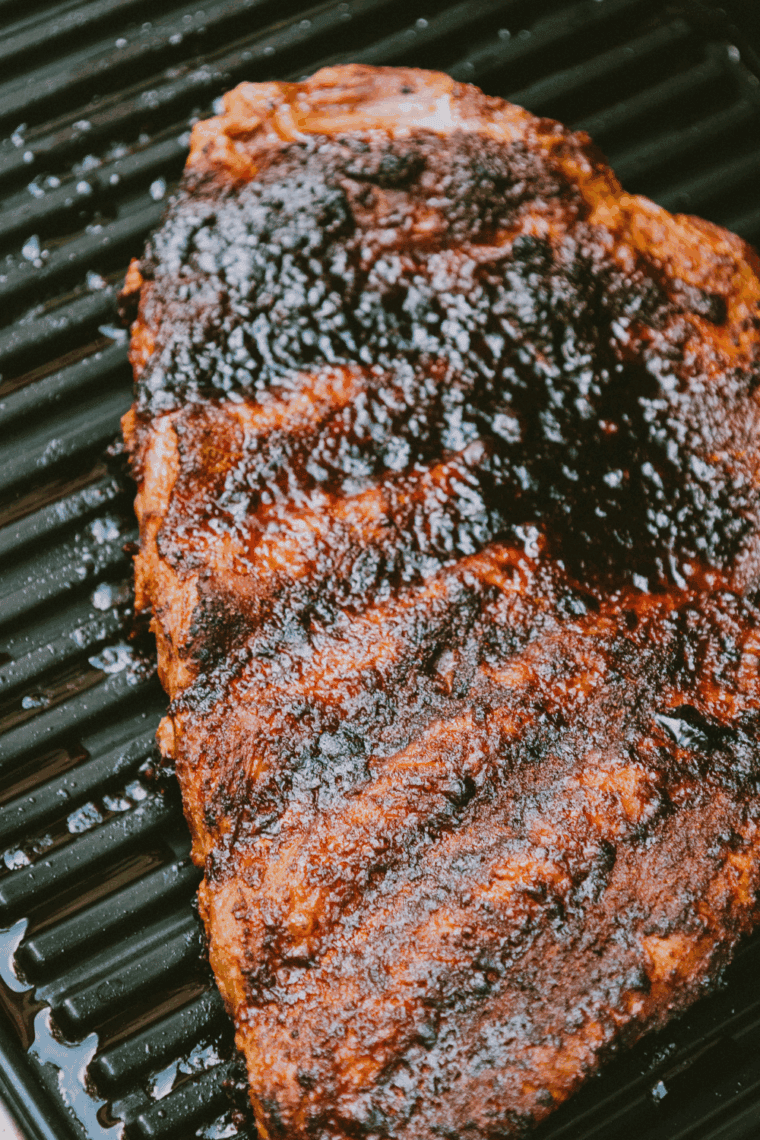 Texas Roadhouse-style baby back ribs with BBQ glaze and charred edges on a serving plate.