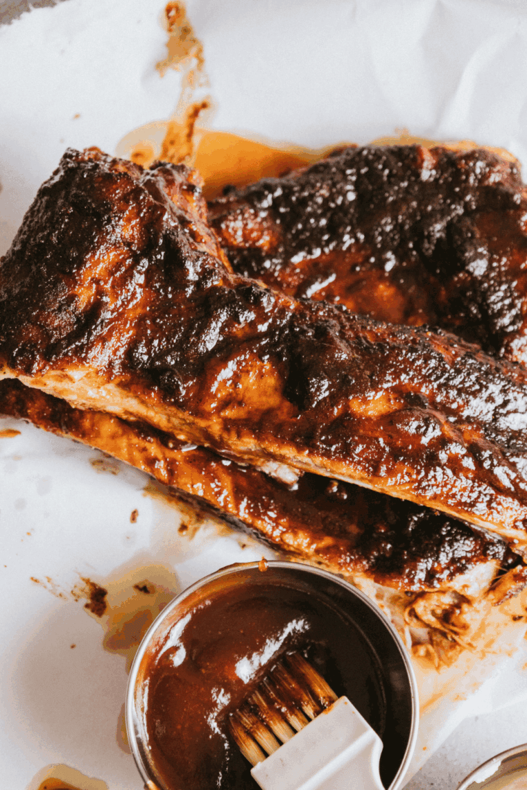 Juicy baby back ribs coated in barbecue sauce, served Texas Roadhouse-style on a rustic platter.