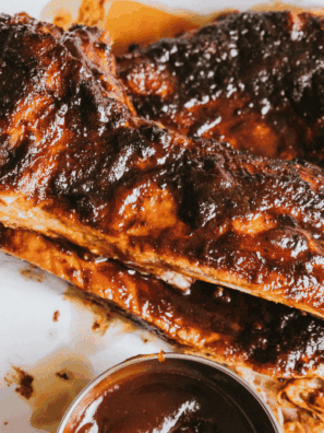 Plate of Texas Roadhouse-style tender ribs glazed with barbecue sauce, served with sides.