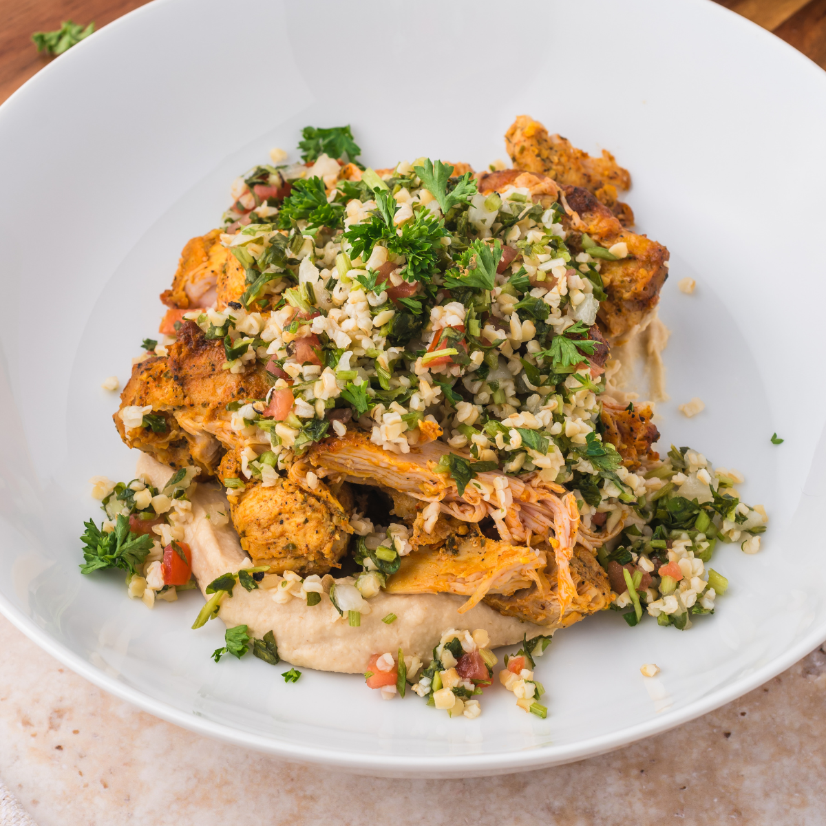 Bowl filled with Trader Joe’s Shawarma Chicken, hummus, and cauliflower tabbouleh, served with fresh vegetables.