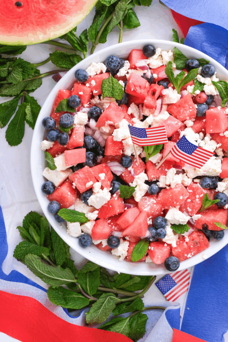 Colorful watermelon salad with feta cheese, cucumber, red onion, and fresh mint served in a white bowl, ready for a summer meal.