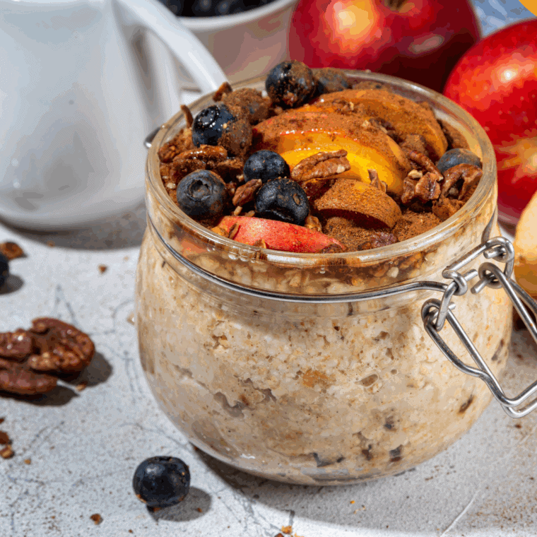 Applesauce overnight oats in a jar with cinnamon and fresh apple slices on top