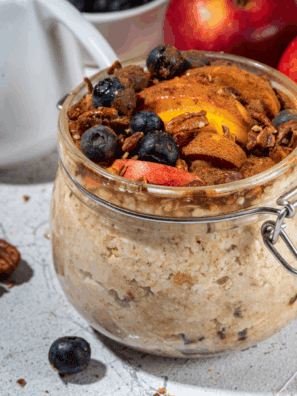 Glass jar filled with applesauce overnight oats topped with fresh apple slices and cinnamon