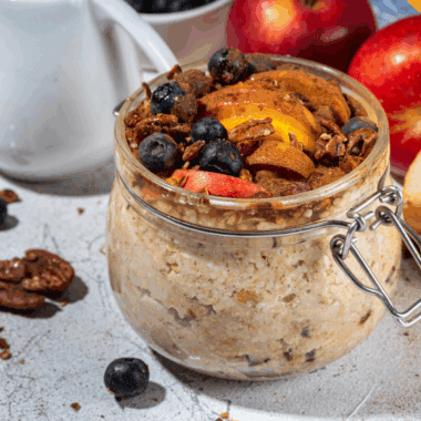 Glass jar filled with applesauce overnight oats topped with fresh apple slices and cinnamon