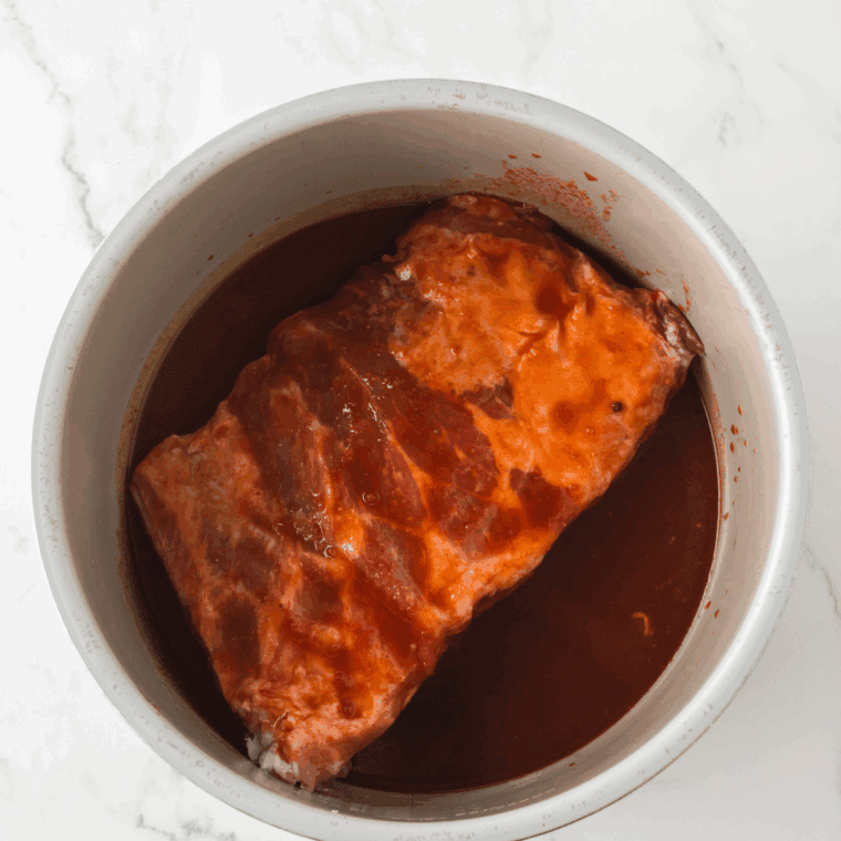 Homemade Arby’s Tangy BBQ Sauce in a bowl with a brush ready for dipping.